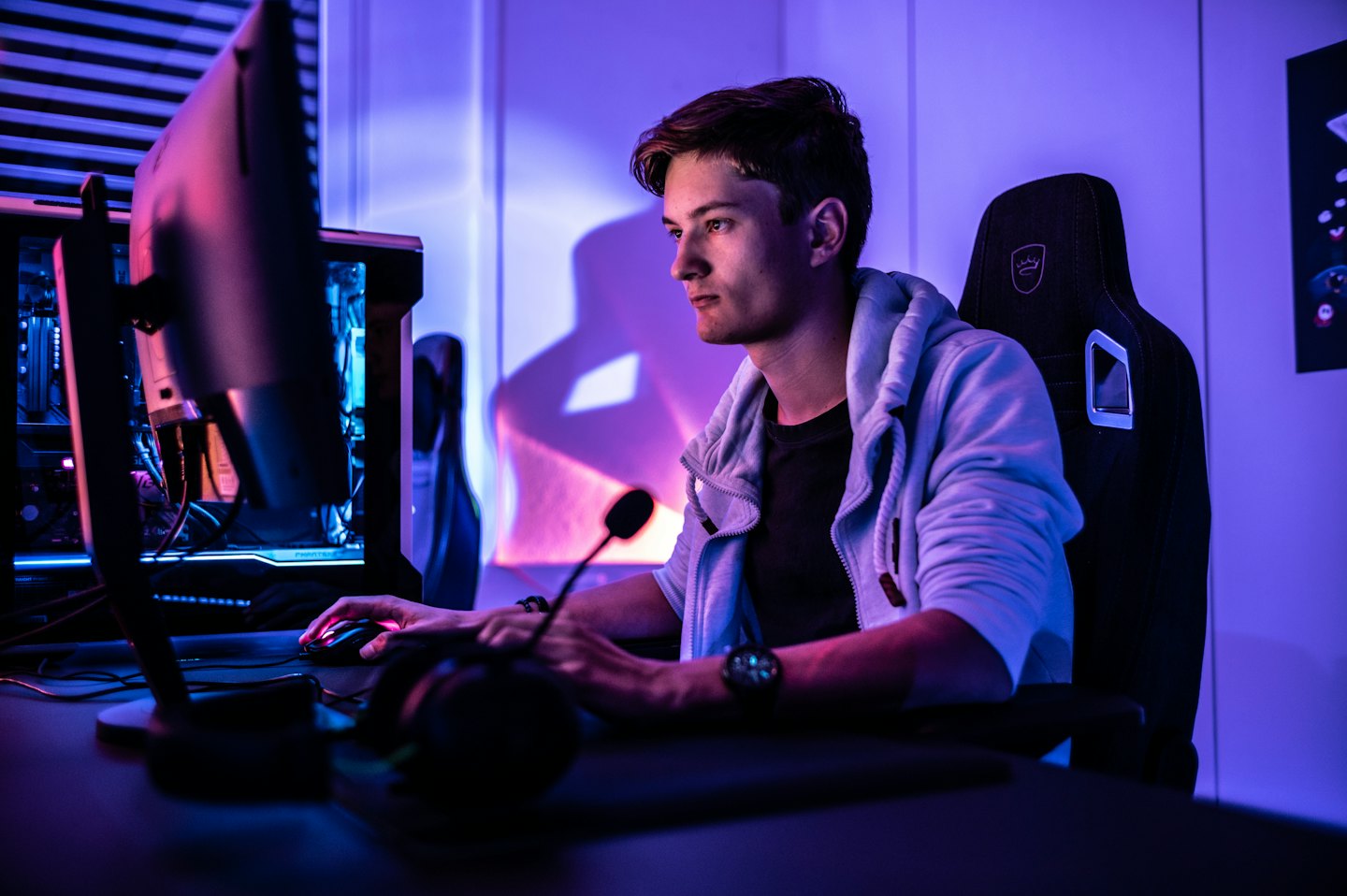 Man intensely focused on a gaming computer in neon light.